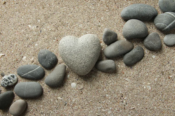 Kum zemin üzerinde kalp şeklinde gri taş — Stok fotoğraf