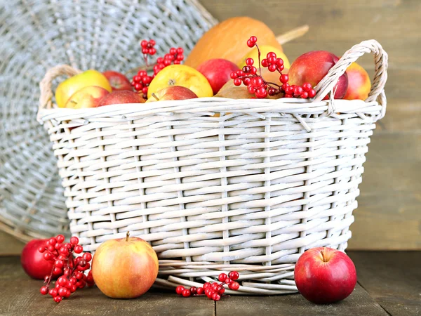 Сочные яблоки и тыква в деревянной корзине на столе крупным планом — стоковое фото