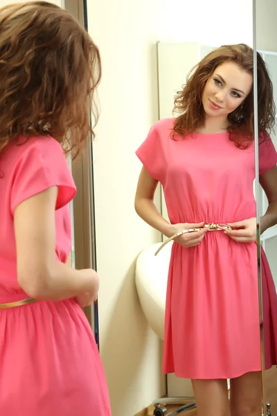 Menina bonita tentando vestido perto do espelho no quarto — Fotografia de Stock