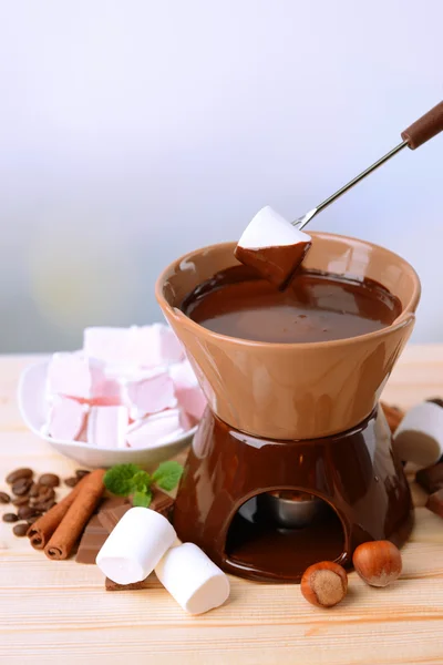 Chocolate fondue with marshmallow candies, on wooden table, on light background — Stock Photo, Image