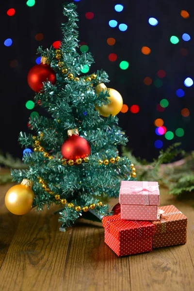 Árvore de Natal decorativa com presentes na mesa em fundo brilhante — Fotografia de Stock