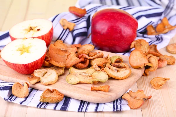 Manzanas secas, sobre tabla de cortar, sobre fondo de madera de color — Foto de Stock