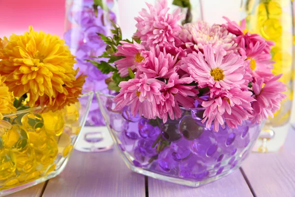Hermosas flores en jarrones con hidrogel en la mesa de cerca —  Fotos de Stock
