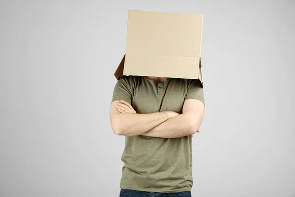 Man with cardboard box on his head on grey background — Stock Photo, Image