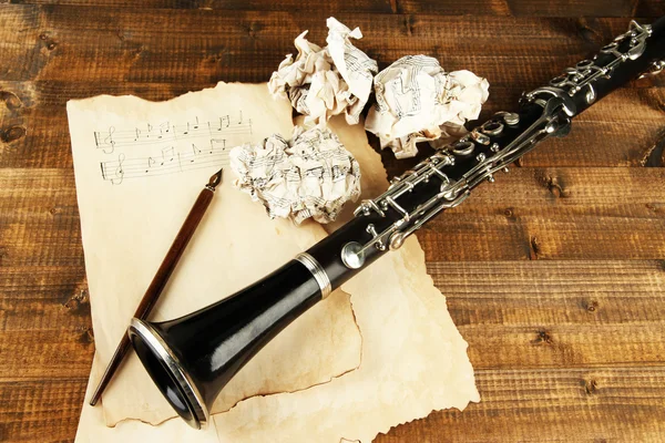 Crumpled paper balls with music sheets and clarinet on wooden background — Stock Photo, Image