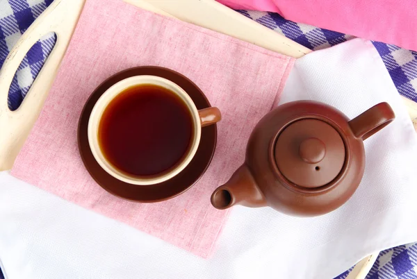 Tasse und Teekanne auf Holztablett auf Stoffhintergrund — Stockfoto