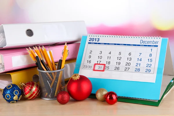 Table with office supplies, calendar and Christmas tinsel close-up — Stock Photo, Image