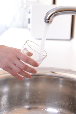 mutfak musluk elini tutarak bardak su döktü
