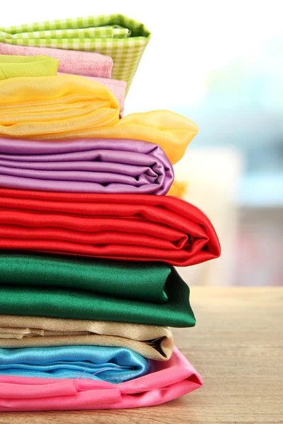 Heap of cloth fabrics on wooden table — Stock Photo, Image