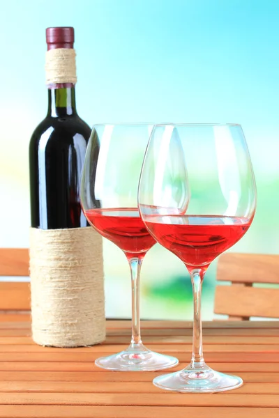 Glasses of wine on wooden table on nature background — Stock Photo, Image