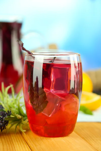 Red basil lemonade in jug and glass, on wooden table, on bright background — Stock Photo, Image