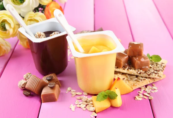 Gustosi dessert alla panna con pezzi di frutta fresca, biscotti e scaglie, su sfondo di legno a colori — Foto Stock