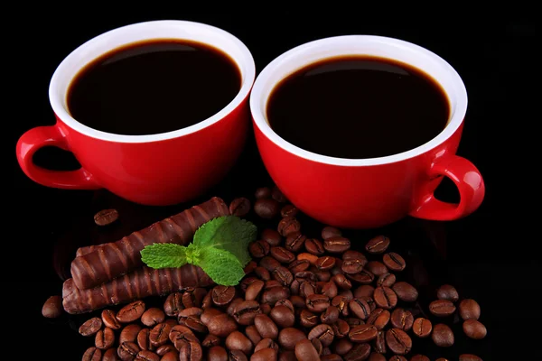 Rote Tassen starken Kaffees mit Kaffeebohnen und Schokoriegeln aus nächster Nähe — Stockfoto