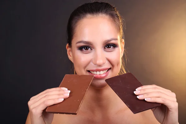 Portrait of beautiful young girl with chocolate on brown background — Stock Photo, Image