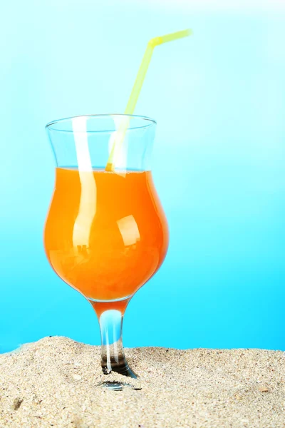 Beach cocktail in sand on blue background — Stock Photo, Image