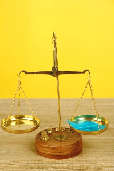 Ισορροπία κλίμακα με φτερό στο τραπέζι σε κίτρινο φόντο — Φωτογραφία Αρχείου