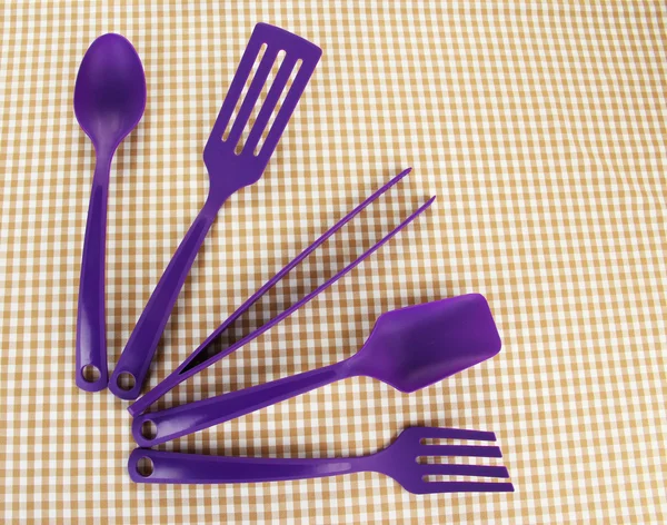 Plastic kitchen utensils on fabric background — Stock Photo, Image