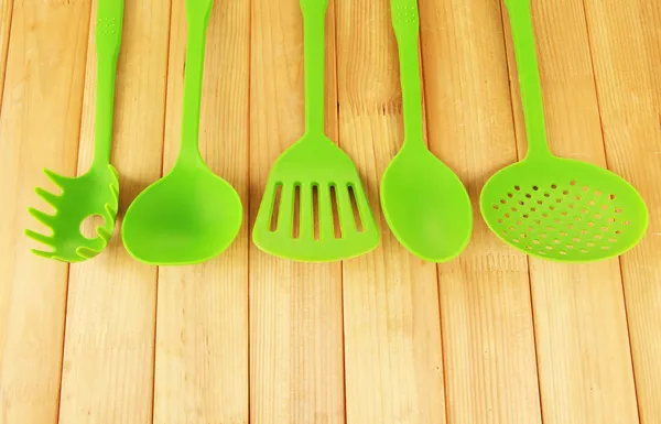 Plastic kitchen utensils on wooden background — Stock Photo, Image