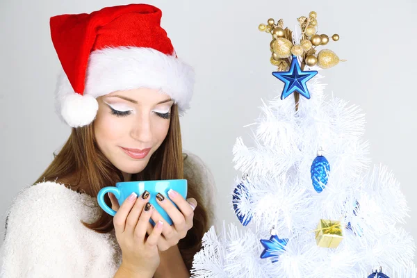 Hermosa chica sonriente cerca del árbol de Navidad con taza —  Fotos de Stock