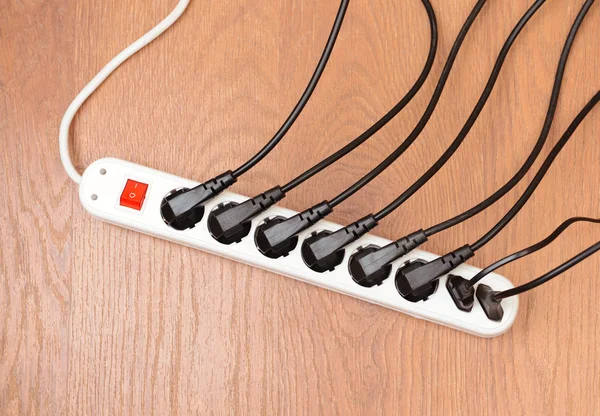 Túlterhelt power board, a fa padló háttér — Stock Fotó