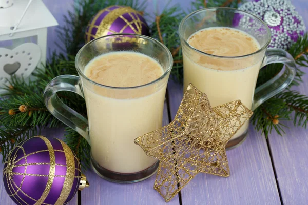 Cups of eggnog with fir branches and Christmas decorations on wooden background — Stock Photo, Image