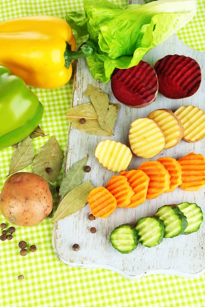 Renkli arka plan üzerinde kesme tahtası üzerinde güzel dilimlenmiş sebze — Stockfoto