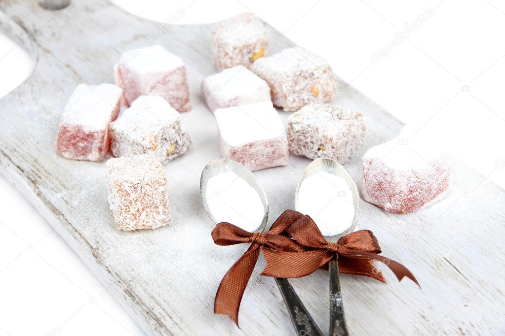 Tasty oriental sweets (Turkish delight) with powdered sugar, on wooden desk
