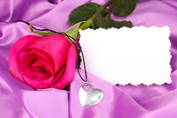 Beautiful pink rose with heart pendant — Stock Photo, Image