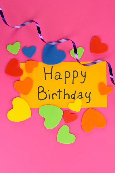 Carta "Buon compleanno" circondato da elementi festivi su sfondo rosa — Foto Stock