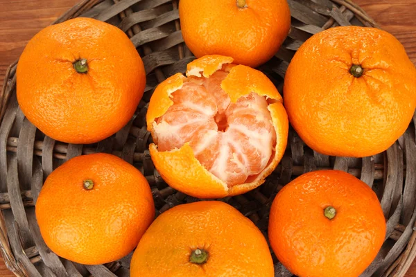 Tasty mandarines on wicker mat on wooden background — Stock Photo, Image