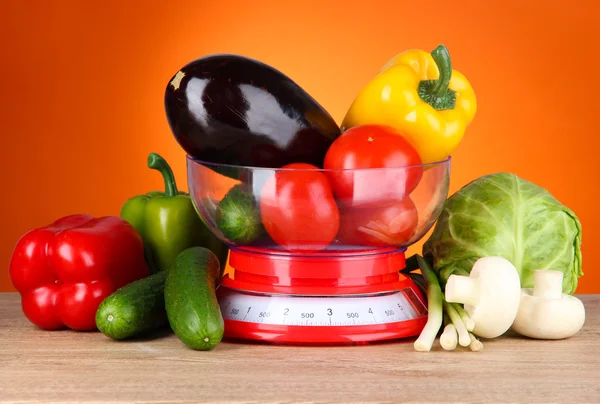 Fresh vegetables in scales on table on orange background — Stock Photo, Image