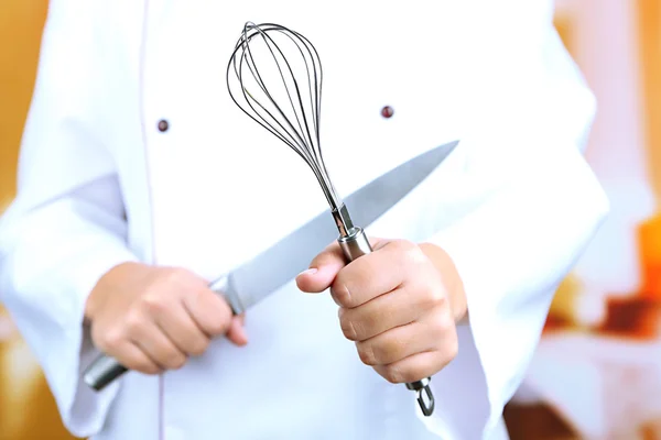 Corola y cuchillo en manos de cocinero sobre fondo brillante — Foto de Stock