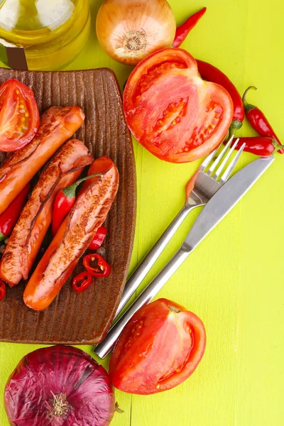 Delicious sausages with vegetables on plate on wooden table close-up — Stock Photo, Image