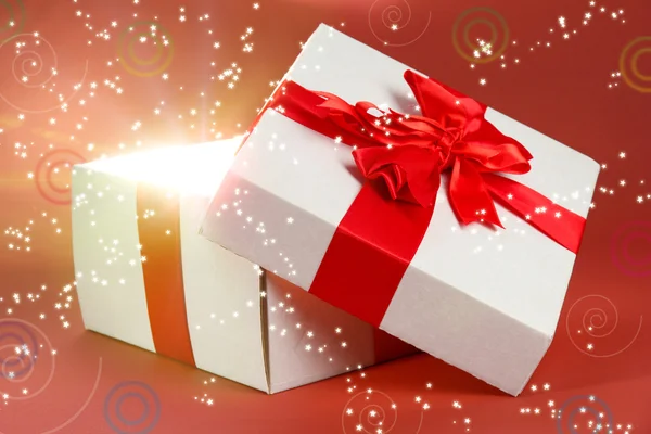 Gift box with bright light on it on red background — Stock Photo, Image