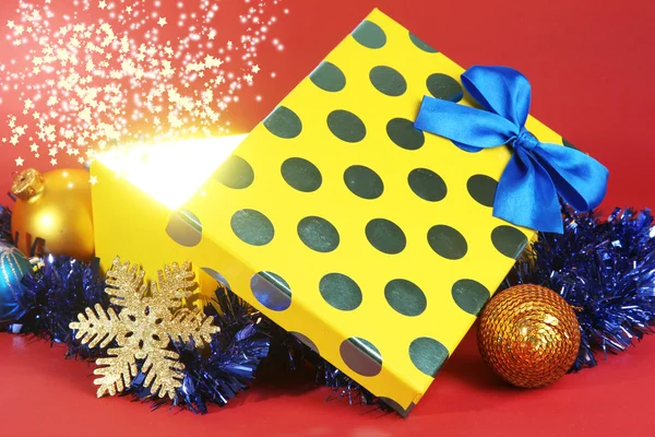 Gift box with bright light on it on red background — Stock Photo, Image