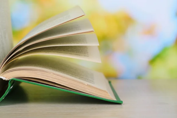 Opened book on wooden table on natural background — Stock Photo, Image