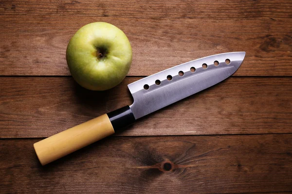 Nóż kuchenny i zielone jabłko, na drewnianym tle — Zdjęcie stockowe