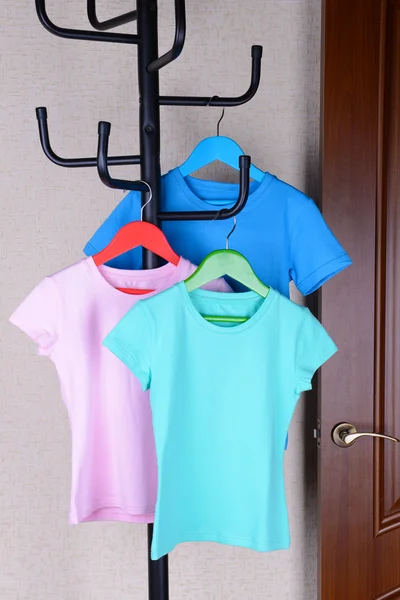 T-shirts penduradas no cabide perto da porta — Fotografia de Stock