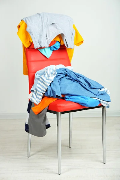 Montón de ropa en silla de color, sobre fondo gris — Foto de Stock