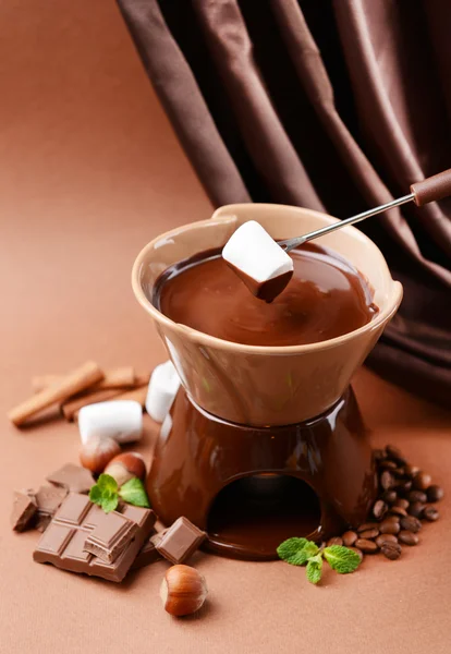 Chocolate fondue with marshmallow candies, on brown background — Stock Photo, Image