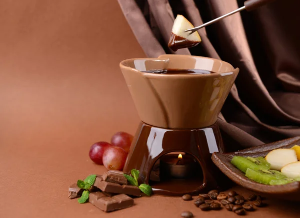 Fondue de chocolate con frutas, sobre fondo marrón —  Fotos de Stock