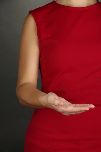 Manos femeninas mostrando algo sobre fondo gris — Foto de Stock