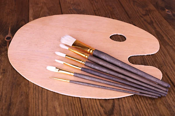 Tavolozza d'arte in legno e pennelli sul tavolo primo piano — Foto Stock