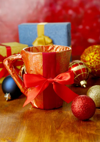 Copa envasada en papel de regalo con regalos en mesa de madera sobre fondo brillante —  Fotos de Stock