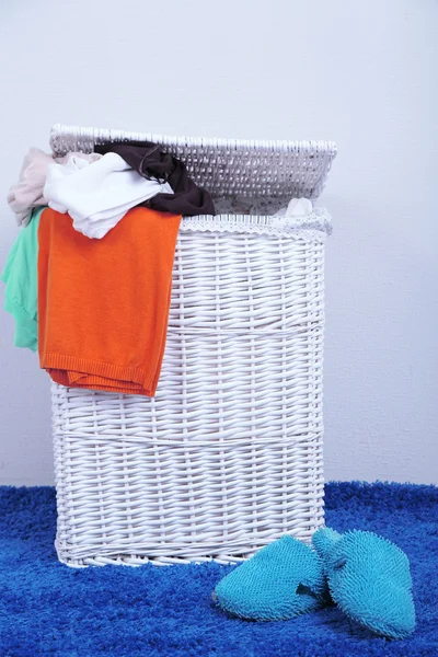 Volledige wasmand op kleur tapijt op grijze muur achtergrond — Stockfoto