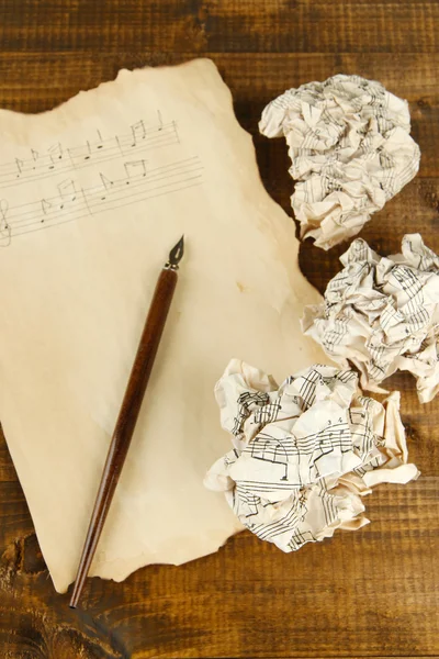 Crumpled paper balls with ink pen and music sheet on wooden background — Stock Photo, Image