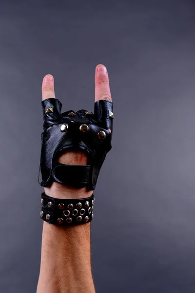 Hand van rocker in lederen armband en mitten, op grijze achtergrond — Stockfoto