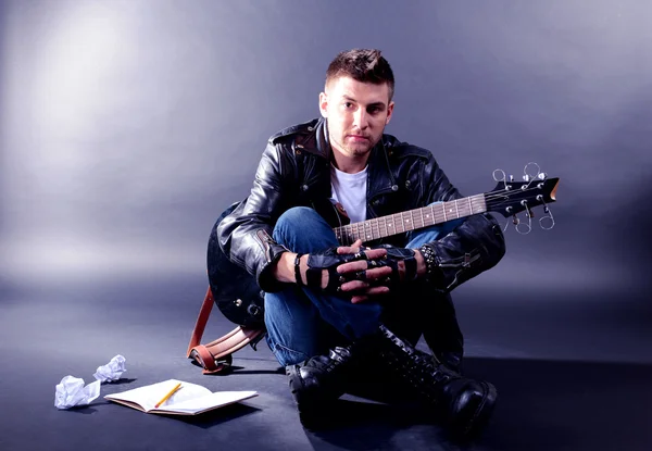 Joven músico tocando la guitarra sobre fondo gris —  Fotos de Stock