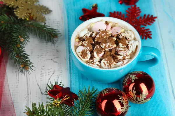 Cioccolata calda con crema in tazza di colore, sul tavolo, su sfondo decorazioni natalizie — Foto Stock