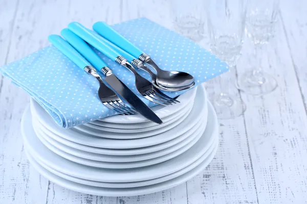 Clean dishes on wooden table on light background